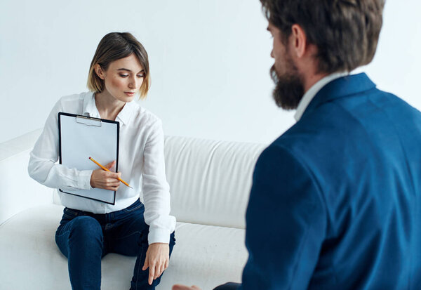 Business man in a classic suit and a woman on the couch with documents in their hands