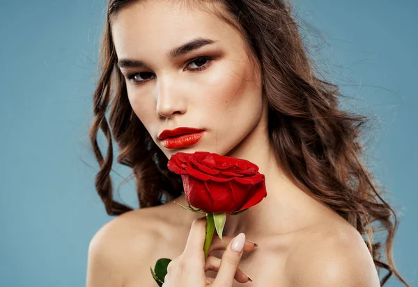 Jolie brune avec une rose rouge près du visage sur un fond bleu — Photo
