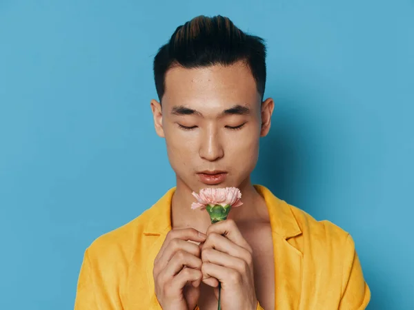 Homem encantador com uma flor clara em um fundo azul e em um casaco amarelo — Fotografia de Stock