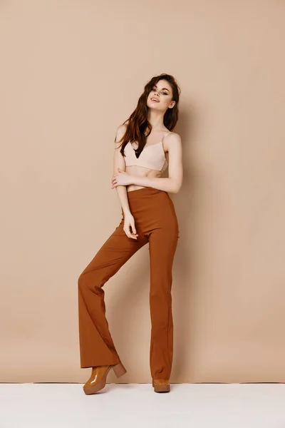 Cute woman in trousers and in a t-shirt on a beige background high heel shoes model — Stock Photo, Image