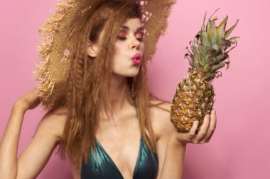 Plaj şapkalı kadın ananaslı egzotik mayo pembe arka plan