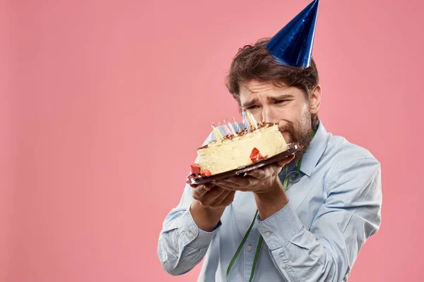 Бородатый мужчина с языком торта на розовом фоне обрезанный вид и синий колпак на голове — стоковое фото