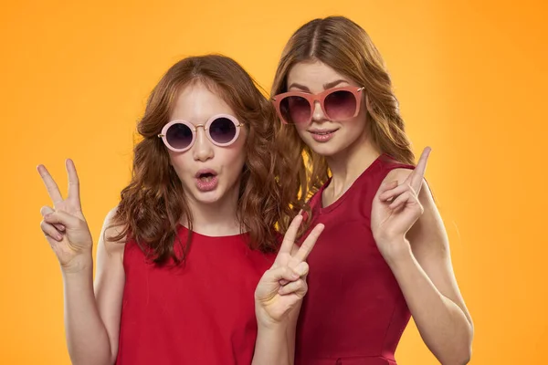 Glad mamma och dotter bär solglasögon livsstil vänskap familj gul bakgrund studio — Stockfoto
