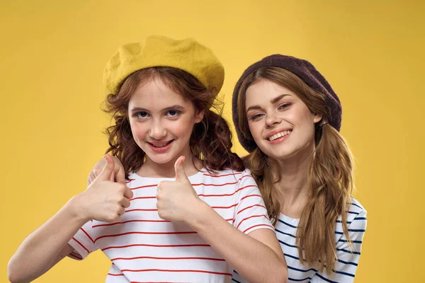 funny mom and daughter wearing hats fashion fun joy family yellow background