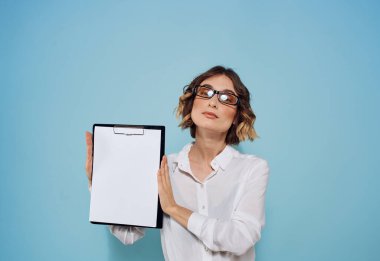 Mavi bir arka plan ve yüzünde gözlük olan beyaz bir sayfa dolusu kadın eli.