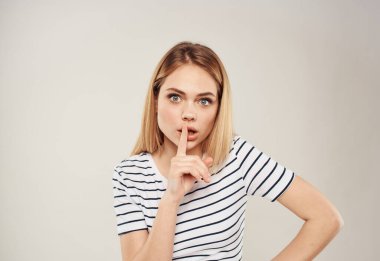 Bej arka planda çizgili tişörtlü neşeli bir sarışının portresi.