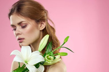 Güzel kadın çiçekleri kozmetik ürünleri çıplak omuzlar pembe arka plan