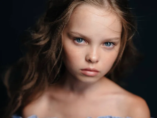 Piękna niebieskooka dziewczyna z gołymi ramionami na ciemnym tle i kręconymi włosami — Zdjęcie stockowe
