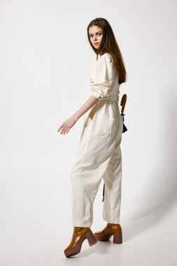 Elinde şemsiyesi olan beyaz elbiseli bir kadın yağmurdan korunuyor.