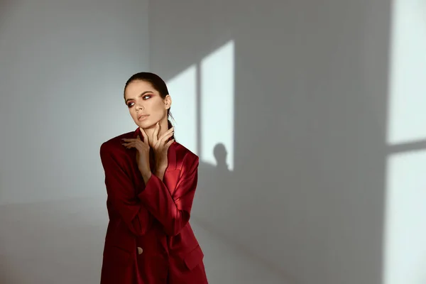 Uma mulher com maquiagem brilhante e uma jaqueta vermelha em um quarto escuro — Fotografia de Stock