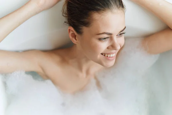 Mulher alegre encontra-se na banheira espuma branca limpa saúde da pele — Fotografia de Stock