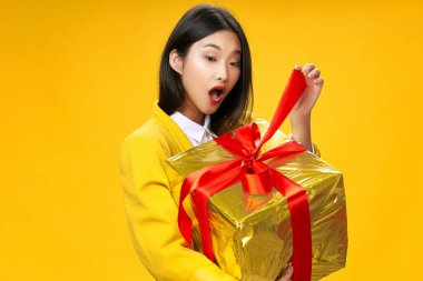 Elinde hediyeyle bir kadın sürpriz sarı arka plan tatili