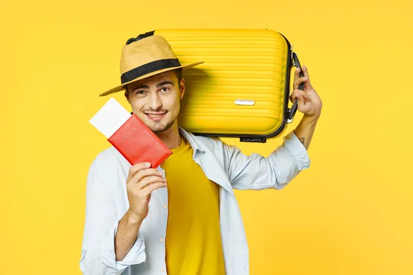 黄色の背景にスーツケースとパスポートを持つ旅行者が — ストック写真