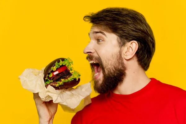 Man met baard in rood t-shirt hamburger snack junk food — Stockfoto