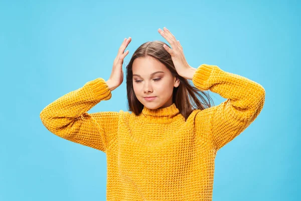 Donna in maglione giallo tiene per mano vicino testa emozioni sfondo blu — Foto Stock