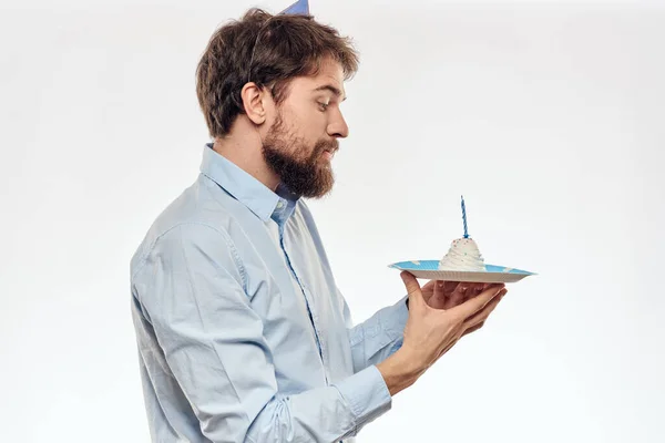 Egy szakállas férfi tortát tart a kezében egy könnyű háttér születésnapon. — Stock Fotó