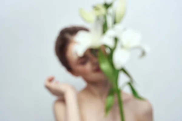 Dame avec un bouquet de fleurs blanches sur un fond gris portrait recadré vue rapprochée — Photo