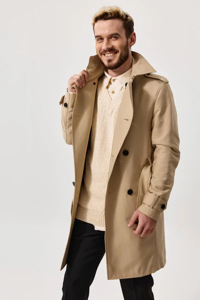 Mężczyzna w beżowym płaszczu i lekkim swetrze na odosobnionym tle portret pozowanie ubrania — Zdjęcie stockowe
