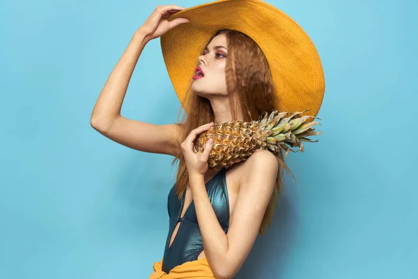 Femme en chapeau de plage ananas tenant maillot de bain fruits exotiques fond bleu vacances — Photo