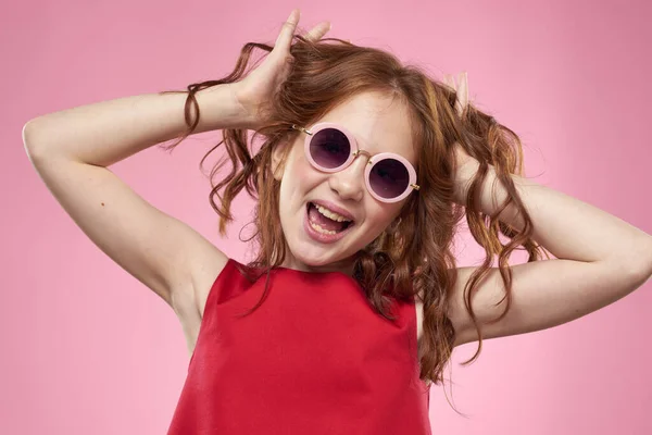 Κορίτσι με σγουρά μαλλιά σκούρα στρογγυλά γυαλιά διασκέδαση κόκκινο φόρεμα ροζ φόντο — Φωτογραφία Αρχείου