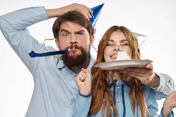 Homme et femme énergique avec un gâteau et chapeaux célébrer un anniversaire sur un fond clair — Photo