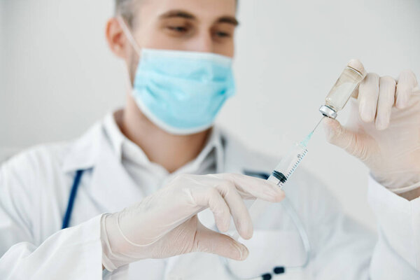 doctor with virus vaccine and medical mask syringe injection light background