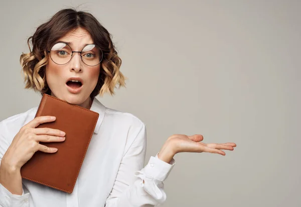 Vrouw op een grijze achtergrond met een boek in haar handen en het dragen van een bril Copy Space — Stockfoto