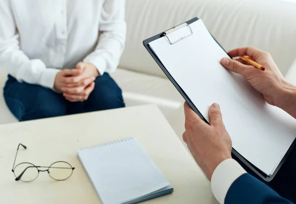 Ein Geschäftsmann mit Dokumenten und eine Frau sitzen auf dem Sofa in einem hellen Raum — Stockfoto