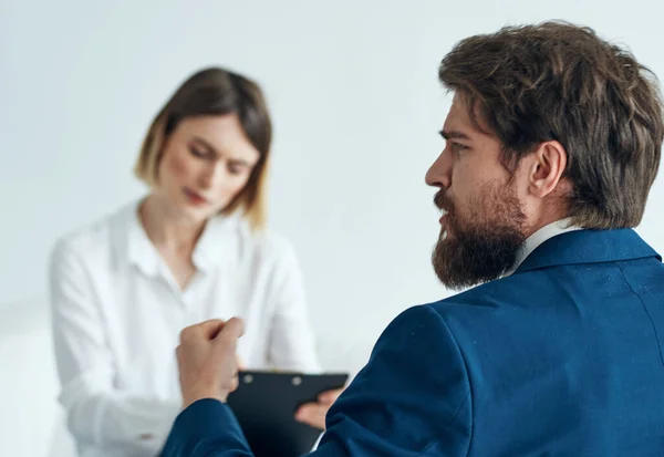 Un uomo d'affari in giacca e cravatta sta gesticolando con le mani e una donna è seduta sul divano — Foto Stock