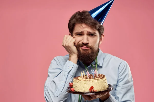 Hombre con una gorra en su cabeza pastel decoración de vacaciones fondo rosa — Foto de Stock