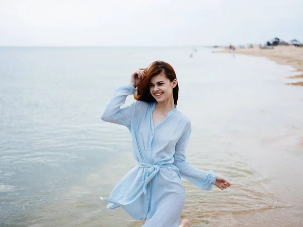 Donna in abito blu in esecuzione sulla riva del mare — Foto Stock