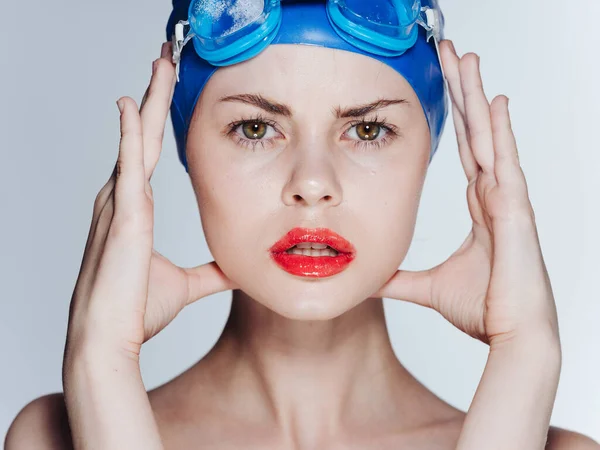 Bella donna con un berretto blu tocca il viso con le mani e gli occhiali — Foto Stock