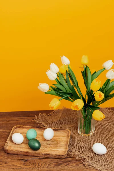 Fleurs dans un vase Pâques oeufs décoration vacances fond jaune — Photo