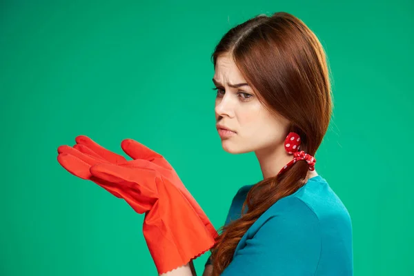 Уборщица в резиновых перчатках держит руки возле лица уборка по дому зеленый фон — стоковое фото
