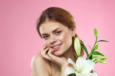 Pembe arka planda çiçekli güzel bir kadın makyaj modeli.