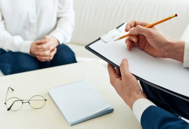 Belgeleri olan bir iş adamı ve bir kadın, parlak bir odada, kanepede oturuyor.