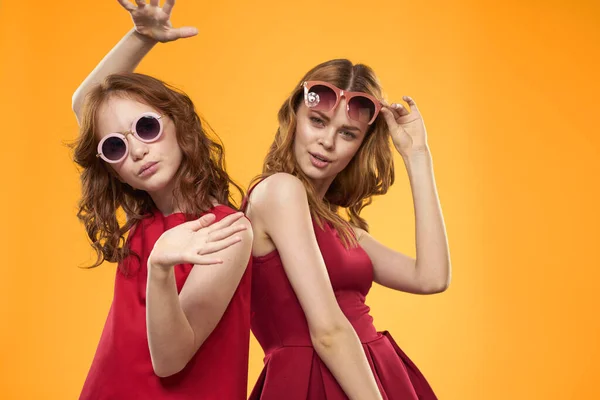 Dwie siostry i zabawne okulary moda Przyjaźń żółty tło rodzina — Zdjęcie stockowe