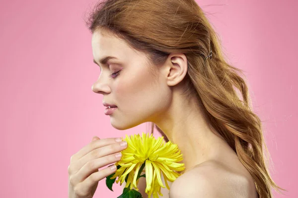 Retrato de uma mulher com flores amarelas em um fundo rosa Maquiagem no rosto — Fotografia de Stock