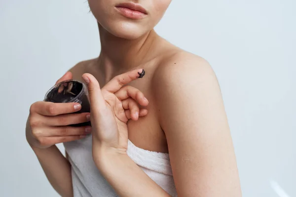 Vacker kvinna i vit handduk svart grädde i händerna hudvård kosmetika närbild — Stockfoto