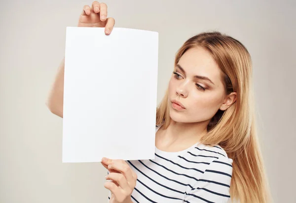 Blondine vrouw met een wit vel papier in de handen van een reclamebanner — Stockfoto