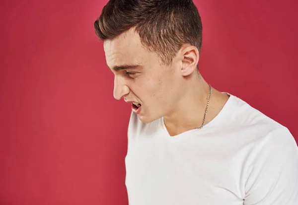 Man in white t-shirt close-up red background dissatisfaction — Stock Photo, Image