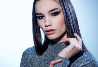 Güzel kadın saç modeli gri kazak elleriyle yüzüne dokunuyor.