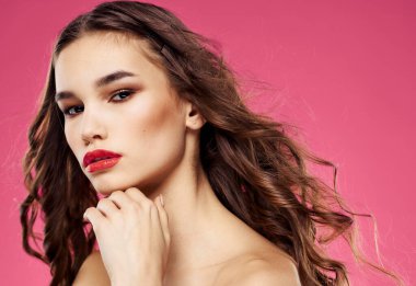 Pembe arka planda parlak makyajlı kırmızı dudaklı zarif bir kadının portresi.