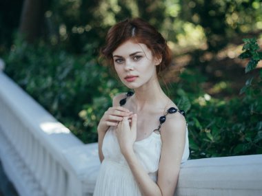 Beyaz elbiseli güzel bir kadın lüks yürüyüş küpeleri takıyor.