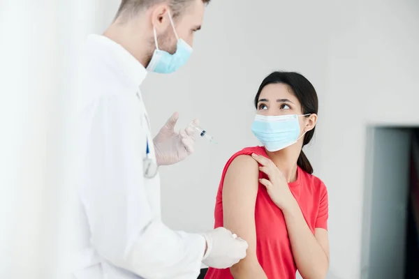Man läkare som håller en spruta i händerna bredvid patienten injektion covid — Stockfoto