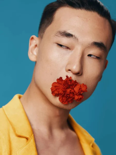 Retrato de un hombre asiático con una flor roja en la boca y una chaqueta amarilla —  Fotos de Stock