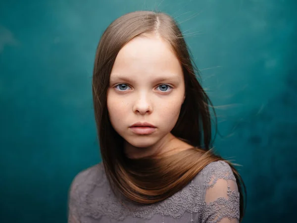 Bella bambina in un abito grigio primo piano ritagliato vista capelli biondi sfondo turchese — Foto Stock