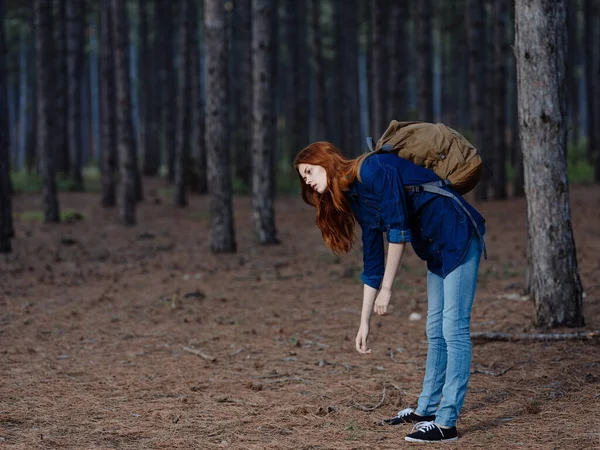 Mujer feliz divirtiéndose en el bosque de pinos con una mochila en la espalda —  Fotos de Stock