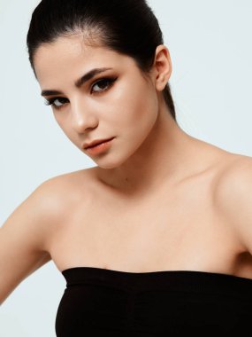 Siyah elbiseli bir kadının portresi. Yüz makyajı ve koyu renk saç modeli.