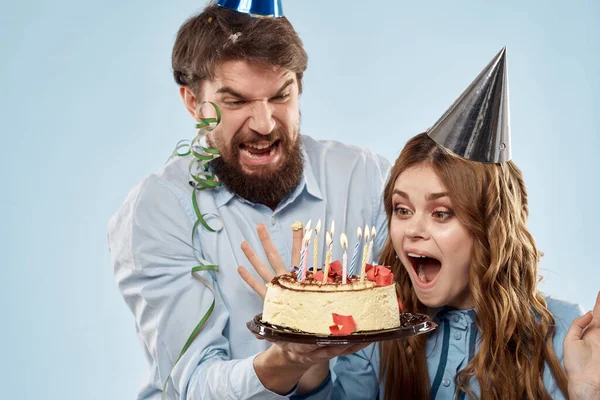 생일 파티 모자를 쓴 남자 파란색 배경에 촛불이 달린 케이크 — 스톡 사진